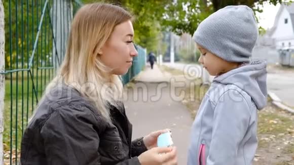 一个带着孩子的女孩戴着防护医疗面罩站在路上街道上弥漫着浓雾流感的流行视频的预览图