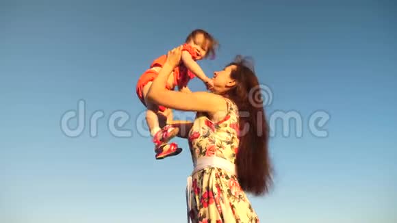 母亲把女儿扔到蓝天上慢动作拍摄妈妈抱着小孩子在天空中玩耍开心快乐视频的预览图