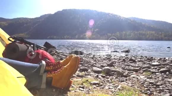 穿着黄色帐篷的旅游靴的女性腿山湖女旅行者上岸要花钱视频的预览图