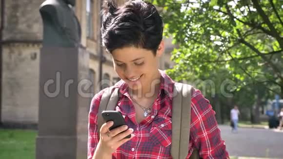 年轻漂亮的女学生留着黑色短发打着电话微笑着站在大学附近的街道上视频的预览图