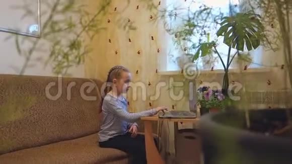 一个小女孩用笔记本电脑工作或玩它视频的预览图