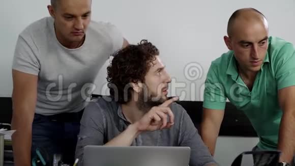 三个成熟迷人的男性正在看着笔记本电脑互相交谈视频的预览图