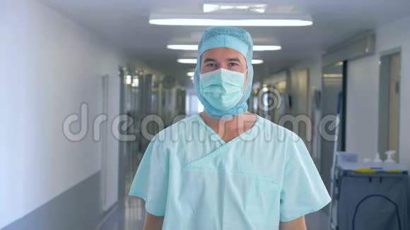 诊所的外科医生男外科医生一边看着摄像机一边收起防护面罩视频的预览图