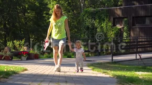 母亲和女儿走在公园小路上视频的预览图