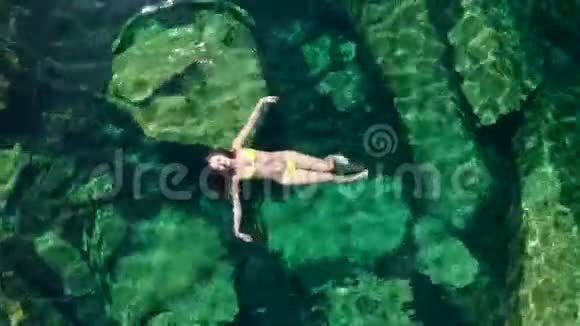 年轻的黑发女人在墨西哥的一个自然的塞诺特游泳池里漂浮和玩耍视频的预览图
