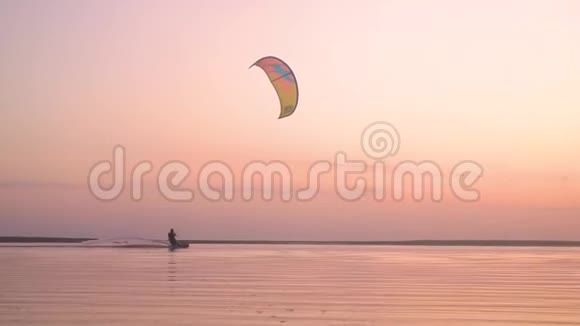 日落时分在水面上表演特技动作的男风筝剪影视频的预览图