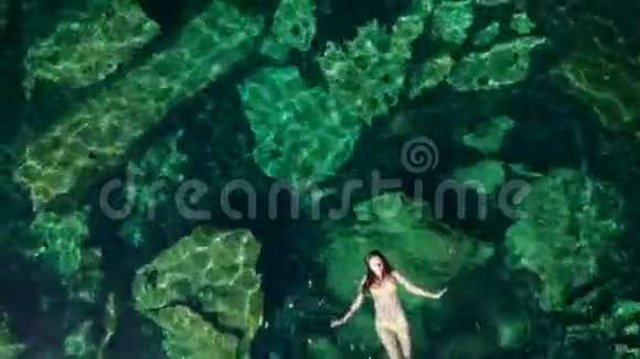 年轻的黑发女人在墨西哥的一个自然的塞诺特游泳池里漂浮和玩耍视频的预览图