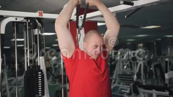 肌肉男在健身房锻炼时做缆绳肱三头肌向下推运动视频的预览图