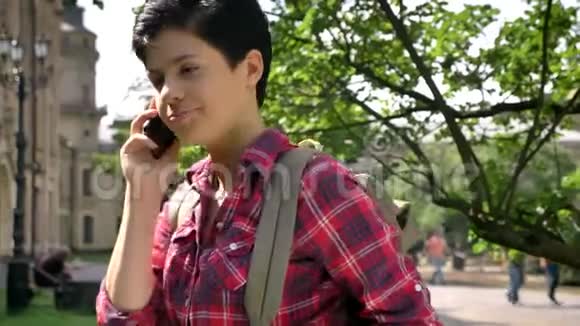 有梦想有思想的女大学生打电话站在大学附近的街道上微笑着视频的预览图
