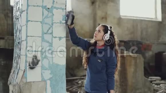 有魅力的女孩专注于用气溶胶涂料在废弃建筑中用涂鸦装饰旧的脏柱视频的预览图