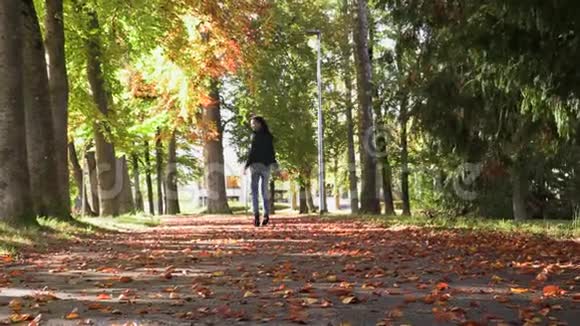 美丽的黑发女孩走在小巷的秋天视频的预览图