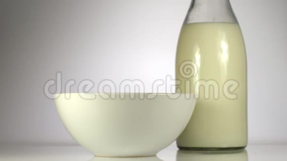 慢动作玉米片落在桌子上牛奶旁边的白色盘子里视频的预览图
