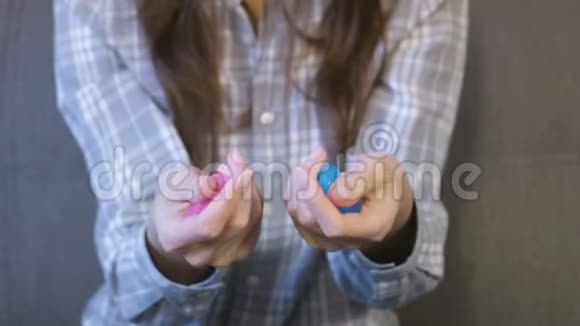 女人手里拿着两粉红色和蓝色的肉泥玩黏液视频的预览图