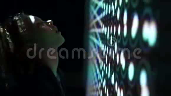 一个孩子看着一个巨大的发光屏幕的顶部上面有抽象的图案未来的技术光的发挥和视频的预览图