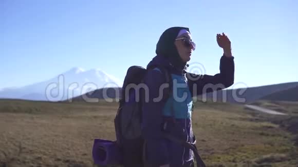年轻的穆斯林游客带着一个大旅游背包在群山的背景下眺望远方视频的预览图