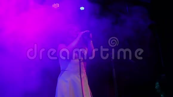 一位年轻的红发歌手带着专业的灯光和烟雾在舞台上唱歌视频的预览图