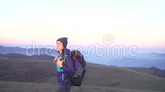 带背包的女游客正在背景山的日落时分旅行视频的预览图