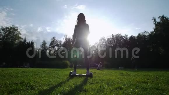 一个夏天在公园的草地上骑着陀螺的美丽苗条的女孩阳光灿烂视频的预览图