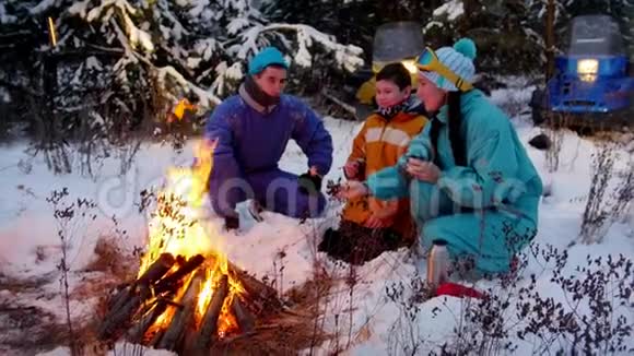 冬季森林一家人坐在火边的树林里互相讲故事视频的预览图