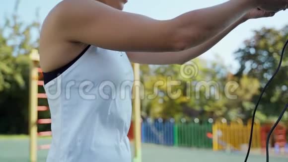 女孩在操场上的院子里跳绳运动活动跳绳的可爱女人视频的预览图