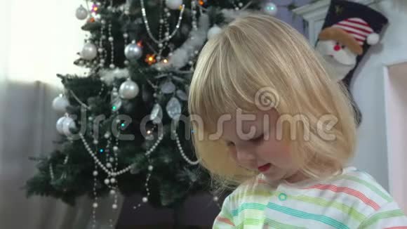 小女孩在圣诞树旁递圣诞礼物视频的预览图
