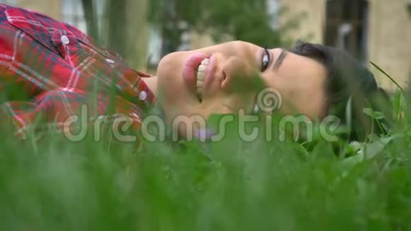 快乐的年轻女子带着美丽的微笑牙齿躺在草地上阳光明媚美丽的大自然白天在户外视频的预览图