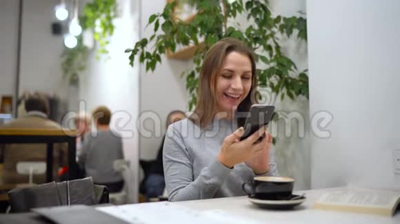 美丽的女人花时间在咖啡馆里为社交网络拍摄照片咖啡和书籍视频的预览图