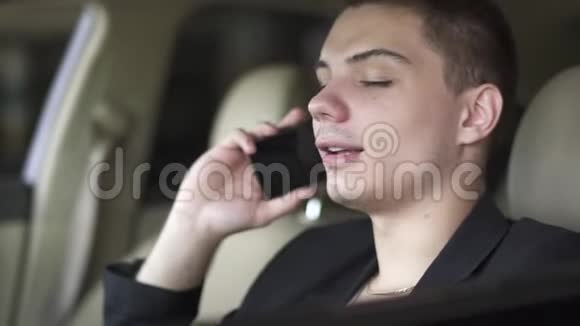 年轻人嚼口香糖和在车里用手机说话的肖像视频的预览图