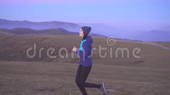 女运动员戴着帽子跑在背景山上慢悠悠视频的预览图