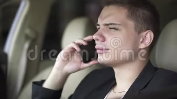 年轻人嚼口香糖和在车里用手机说话的肖像视频的预览图