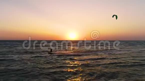 美丽的日落在海上一对风筝冲浪者沿着海浪滑行视频的预览图