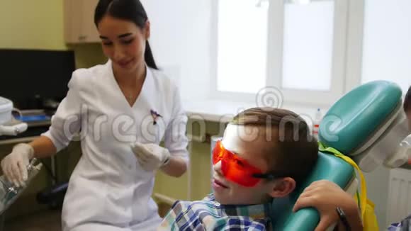 一位年轻的女牙医正在准备治疗牙齿病人和他的孪生兄弟正在微笑视频的预览图