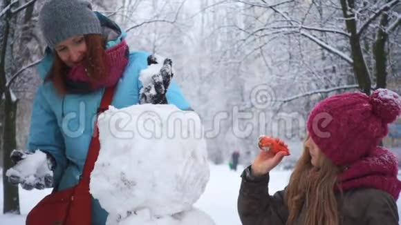 妈妈和她的女儿在下雪的时候玩雪人视频的预览图