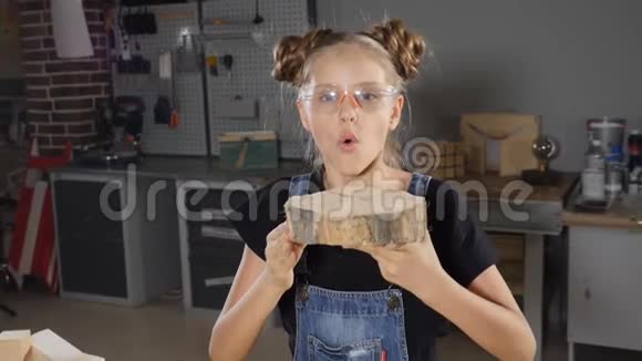 穿着围裙的金发女孩慢吞吞地吹着锯末做木工的孩子Hd视频的预览图