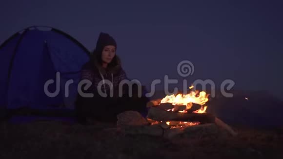 夜里露营的女人坐在帐篷附近在炉火旁晒太阳慢悠悠地说视频的预览图