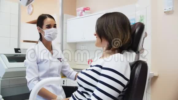 戴口罩的女牙医把椅子和一个女病人倾斜在治疗之前视频的预览图
