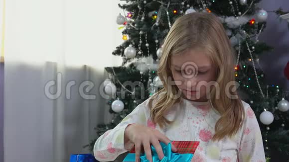 小女孩在圣诞树旁递圣诞礼物视频的预览图