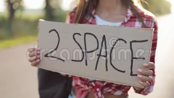 年轻美女搭便车站在路上举着2个空间标志夏季视频的预览图