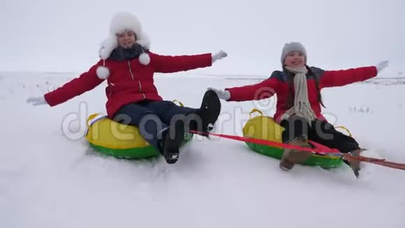 快乐的孩子们骑着雪山在飞行中伸直手臂笑着冬天在雪橇上快乐的童年视频的预览图