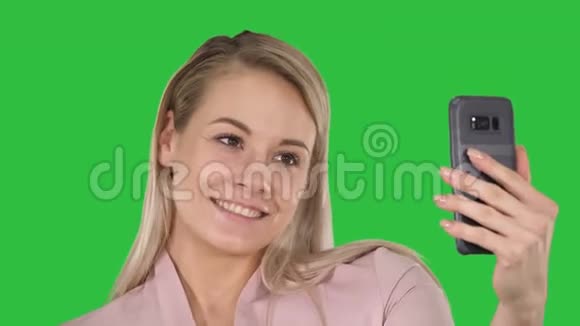 微笑的年轻金发女孩在绿色屏幕上自拍Chroma键视频的预览图