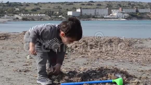 可爱的幼儿在沙滩上玩塑料高尔夫球棒和沙滩海藻视频的预览图