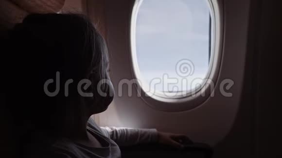 可爱的女孩带着棒棒糖看着飞机上的窗户视频的预览图