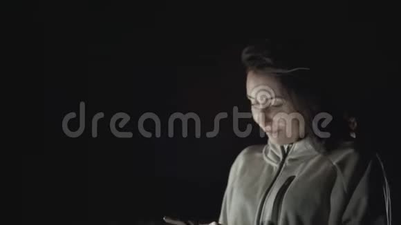 一个带着手机的女孩的肖像在夜城的背景下看着镜头视频的预览图