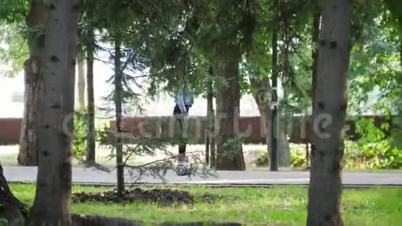 女孩开着摄像机穿过公园里的一个陀螺在树林里视频的预览图