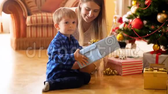4k镜头可爱的3岁小孩早上和妈妈一起打开圣诞礼盒视频的预览图