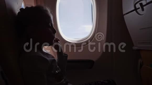 可爱的女孩和棒棒糖坐在飞机上视频的预览图