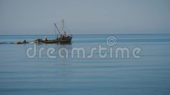 拖船的剪影把一艘小渔船拉到海里视频的预览图