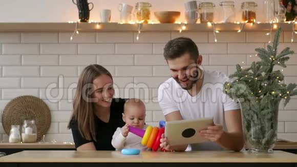 母亲父亲和婴儿的家人坐在家里带着平板电脑视频的预览图