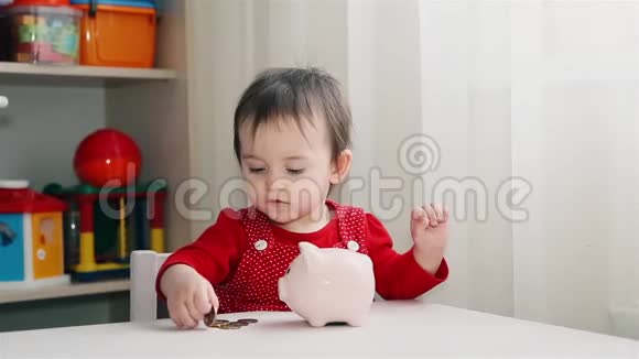 一个穿红衣服的小女孩把硬币扔进了存钱罐视频的预览图