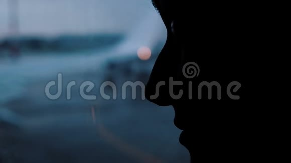 在特写的阴影下一张女性脸的剪影一个女孩在飞机上看着机场潮湿的窗户视频的预览图